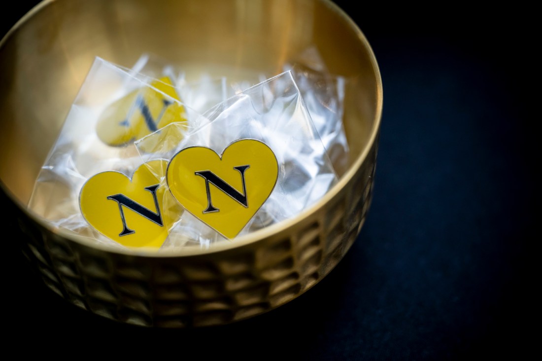 A close-up of a golden bowl containing plastic wrapped yellow heart-shaped items with black 'N' letters on them, representing Northeastern branding. 