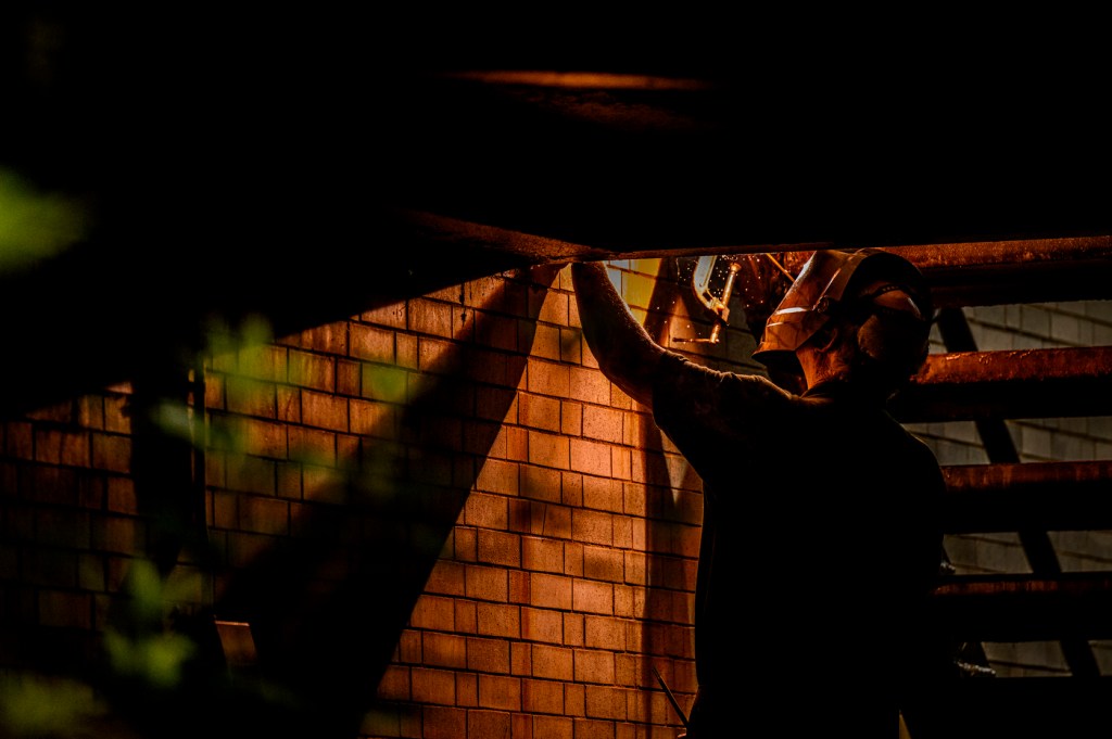A person works with tools in a dimly lit outdoor space.