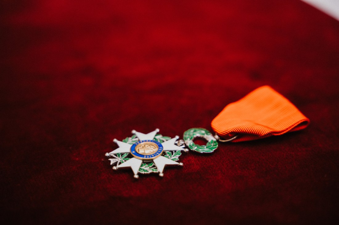 A close-up of France’s Legion of Honour medal with a red ribbon resting on a red velvet surface.