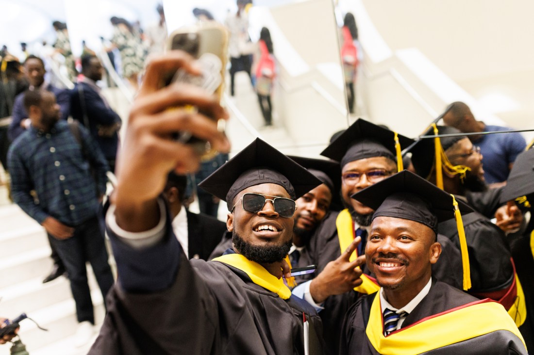 Graduates in caps and gowns smile and pose for a group selfie during Northeastern University Vancouver Campus's Convocation 2025 ceremony at the Centre for the Performing Arts in Vancouver, B.C.