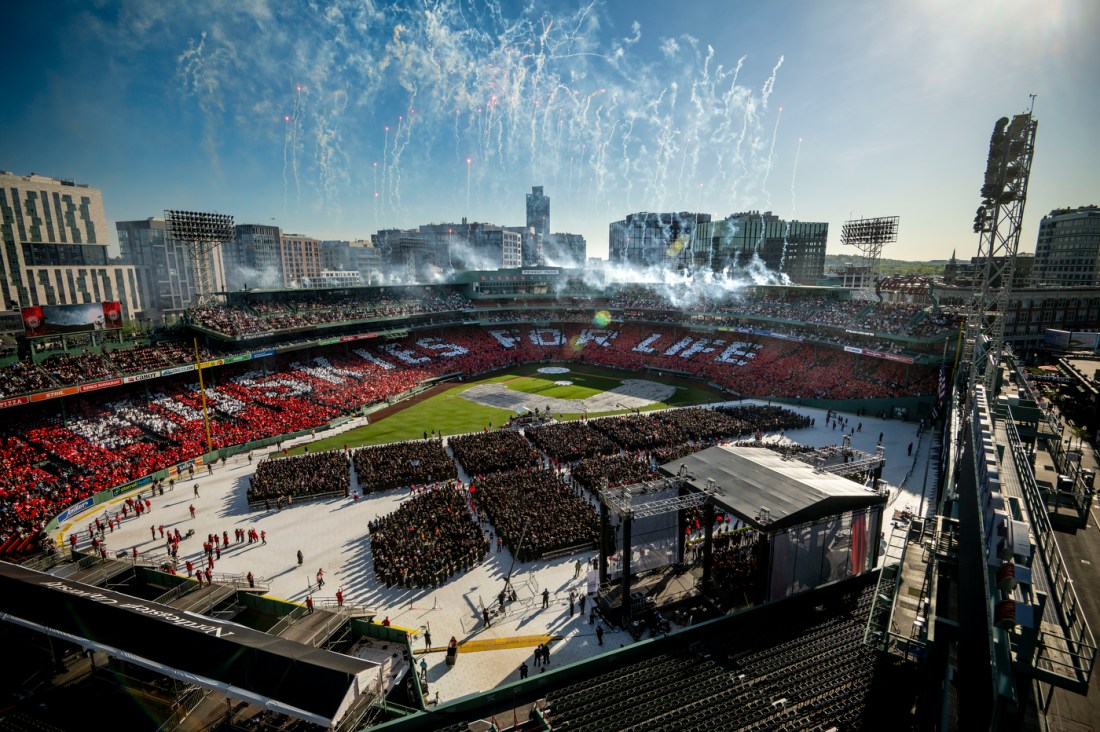 Wide view of Northeastern's 2025 Commencement at Fenway Park, with fireworks in the sky and “HUSKIES FOR LIFE” spelled out in the stands.