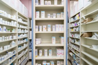 A shelf inside a drug store stocked with prescription drugs.