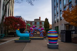Large colorful sculptures seen on the Boston campus at dusk.