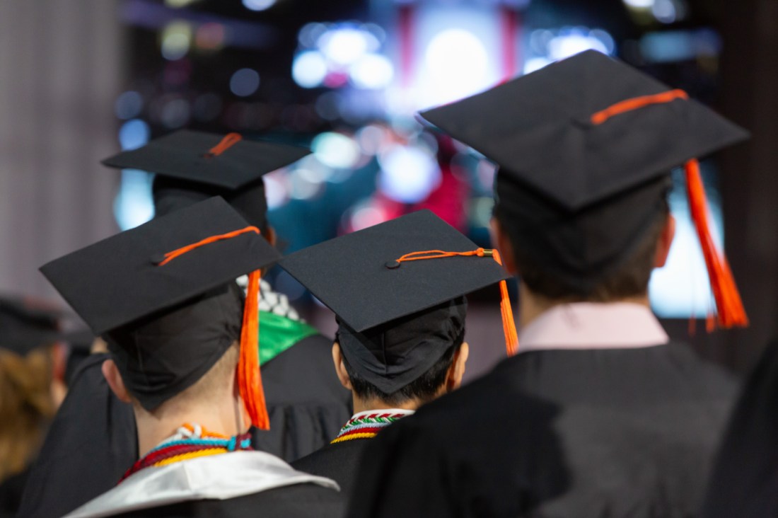 Graduates in caps and gowns gather for engineering ceremony.