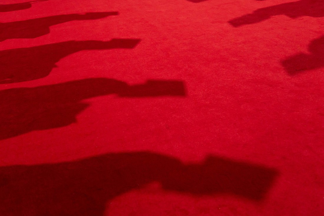  Graduate shadows stretch across red carpet at engineering degree ceremony.