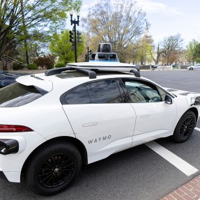 A white self-driving SUV style car on a street in Washington D.C.