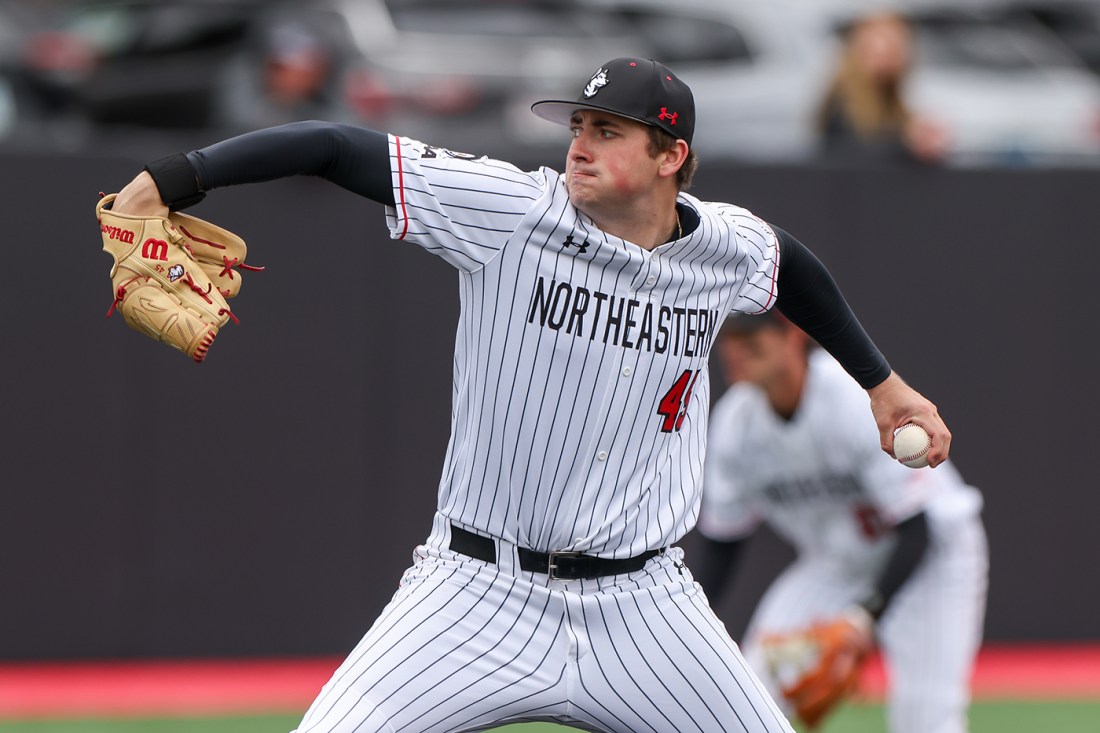 A Northeastern baseball player winds up for a pitch during a game.