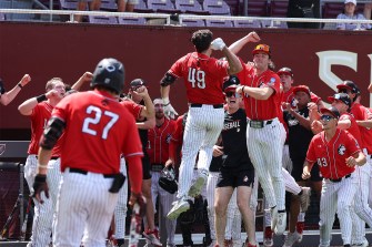 A group of baseball players celebrates near the dugout during a game.