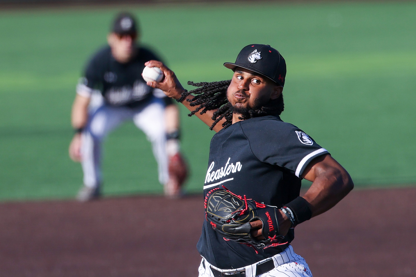 A Northeastern mens baseball player pitches the ball. 