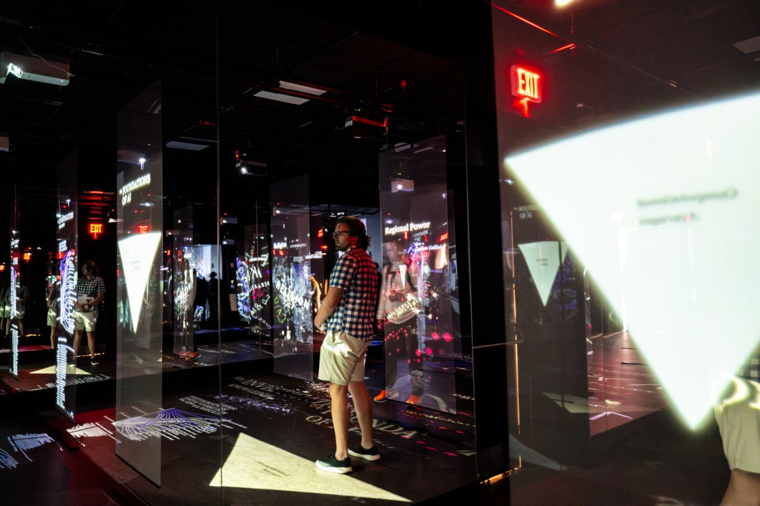 Dimly lit hallway filled with reflective surfaces and digital light projections during an immersive gallery installation.