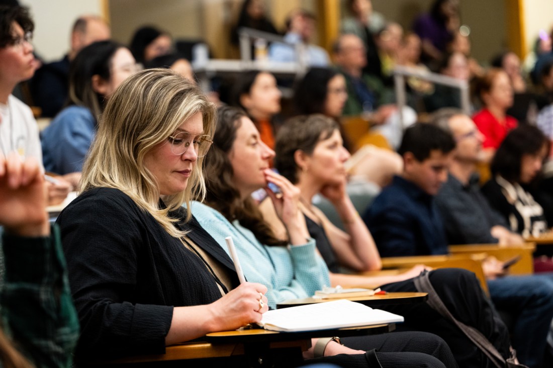 Audience members listen during a presentation inside a lecture hall about COVID misinformation.