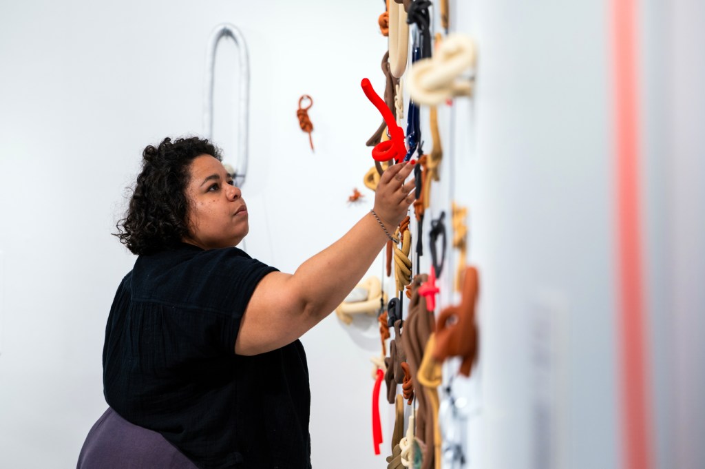 A person adjusts a wall display in a brightly lit gallery space.