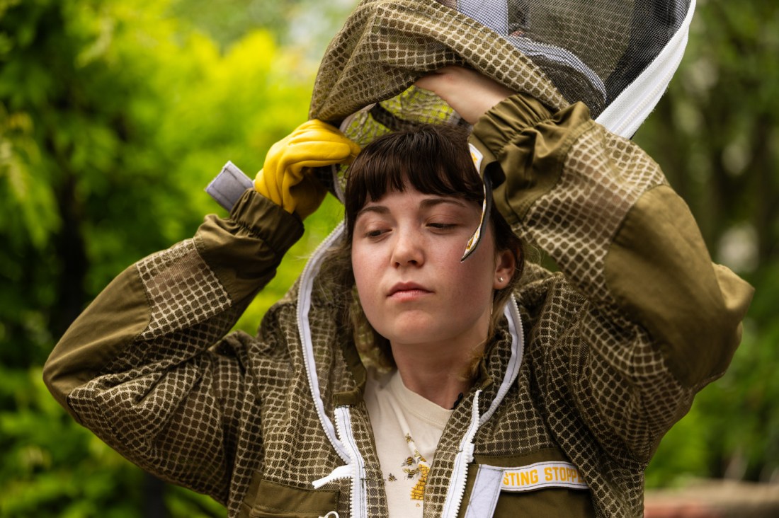 A student beekeeper prepares her suit before working with hives, demonstrating how to start beekeeping safely.
