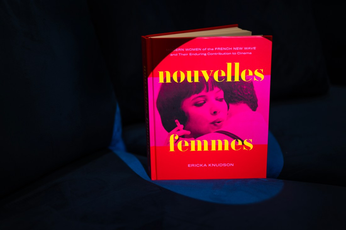 The brightly-colored book "Nouvelles Femmes" standing upright on a dark chair on a black background.