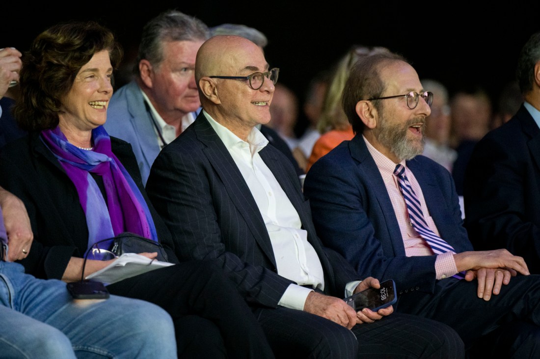 Audience members smile during a conference session on AI and education.
