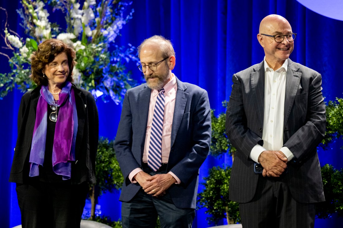Three panelists, including President Aoun, stand on a stage during an conference AI and education.