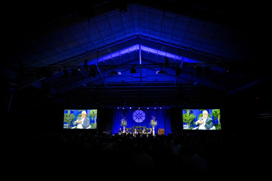 Audience watches a presentation on lifelong learning and AI in a large event space.