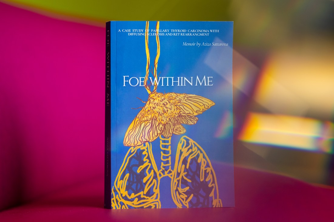 Close-up of a blue book titled 'Foe Within Me' with golden anatomical illustration on the cover. 