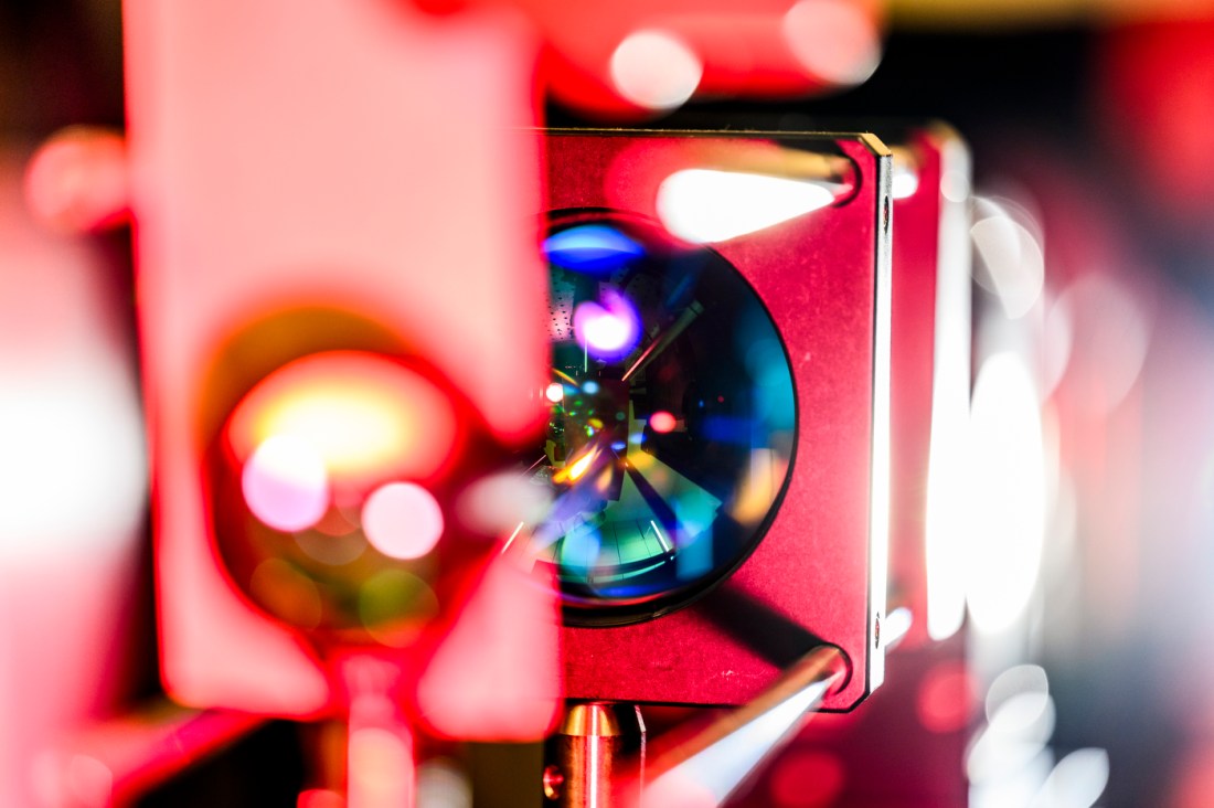 Vibrant red-hued optical device with a reflective lens used in quantum experiments.