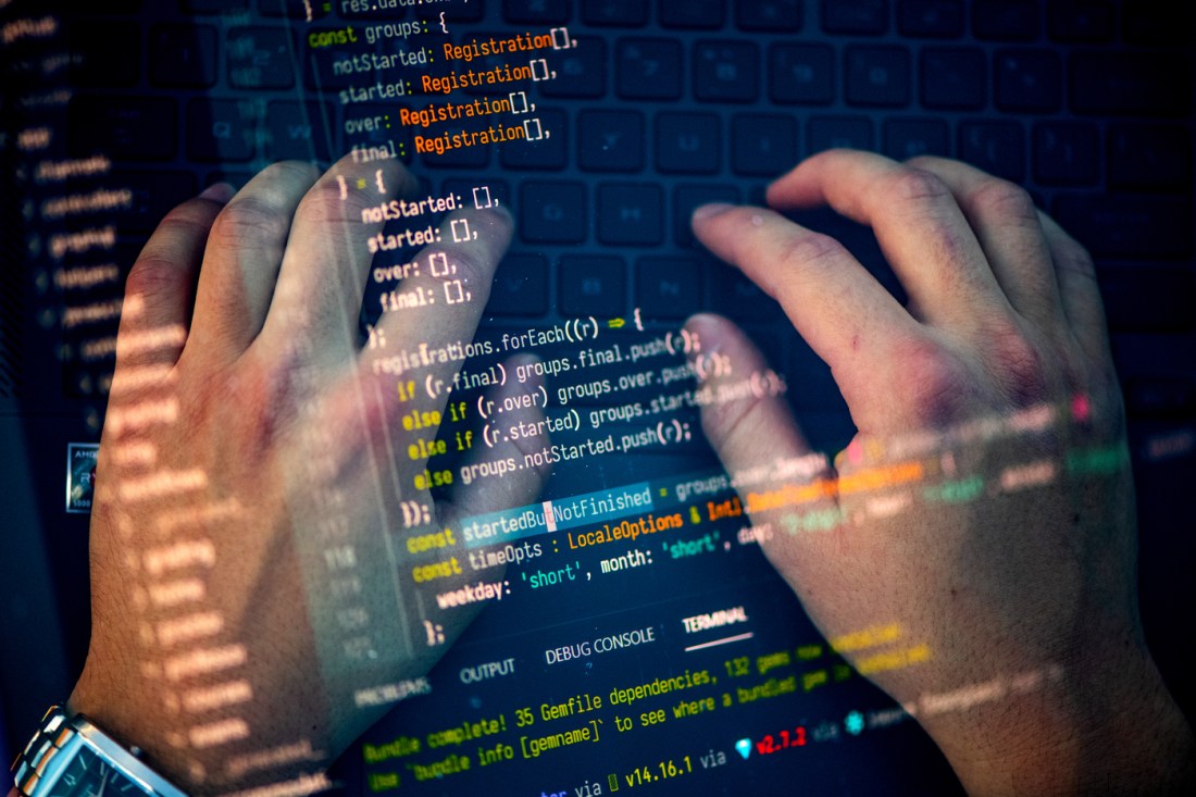 Two hands typing on a laptop. This image is overlaid with another that shows lines of code.