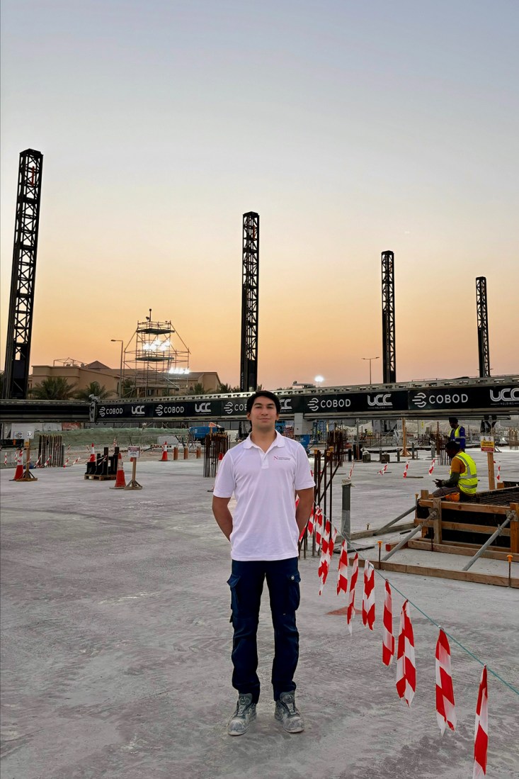 Northeastern student Fernando Escobar stands in front of a construction site in Qatar.
