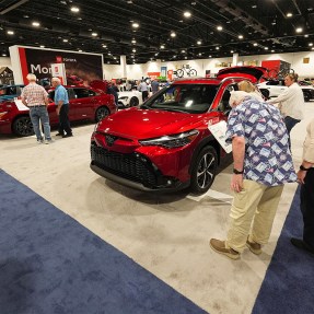 People examine vehicles on display at an auto show.