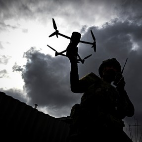 The silhouette of a person and a drone is shown against the backdrop of dark clouds.