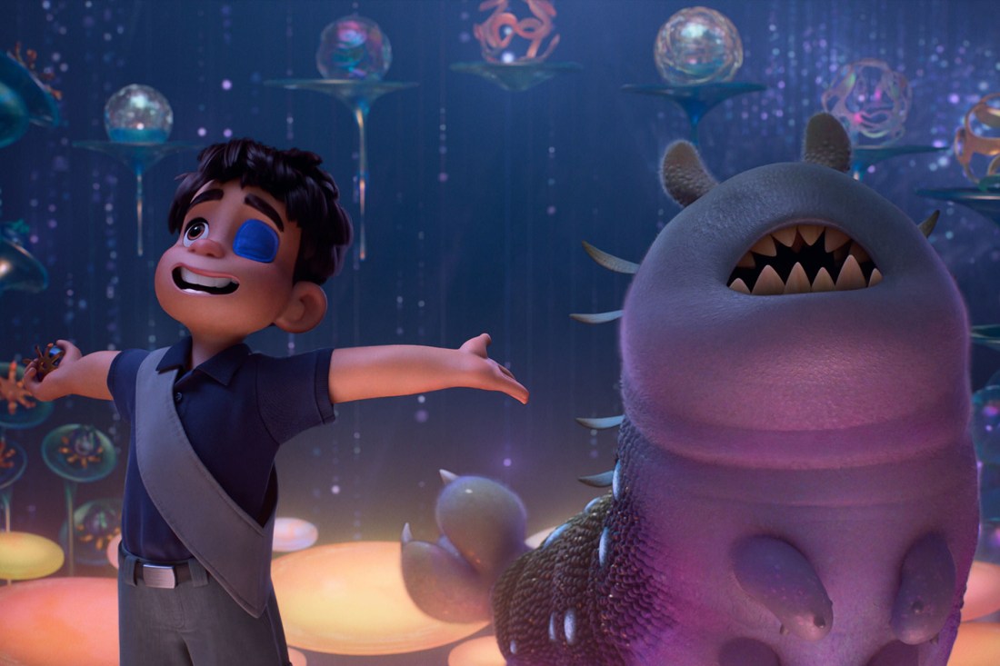 Animated character with a bandage over one eye stands joyfully next to a smiling alien creature in a colorful, otherworldly setting from the movie "Elio."