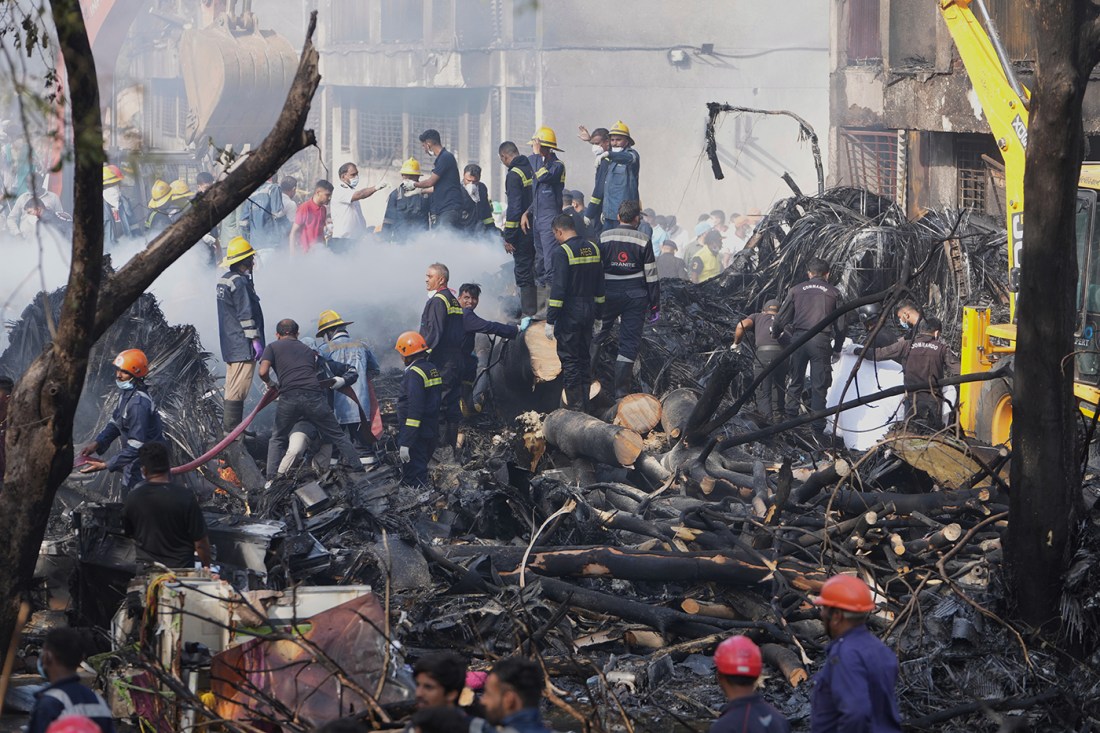 Rescue personnel search through the wreckage of the Air India crash site.