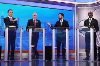 People speak at podiums during a mayoral debate in New York City.