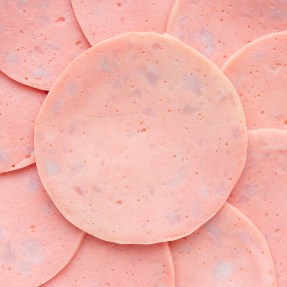 Close-up view of multiple slices of bologna arranged in overlapping layers.