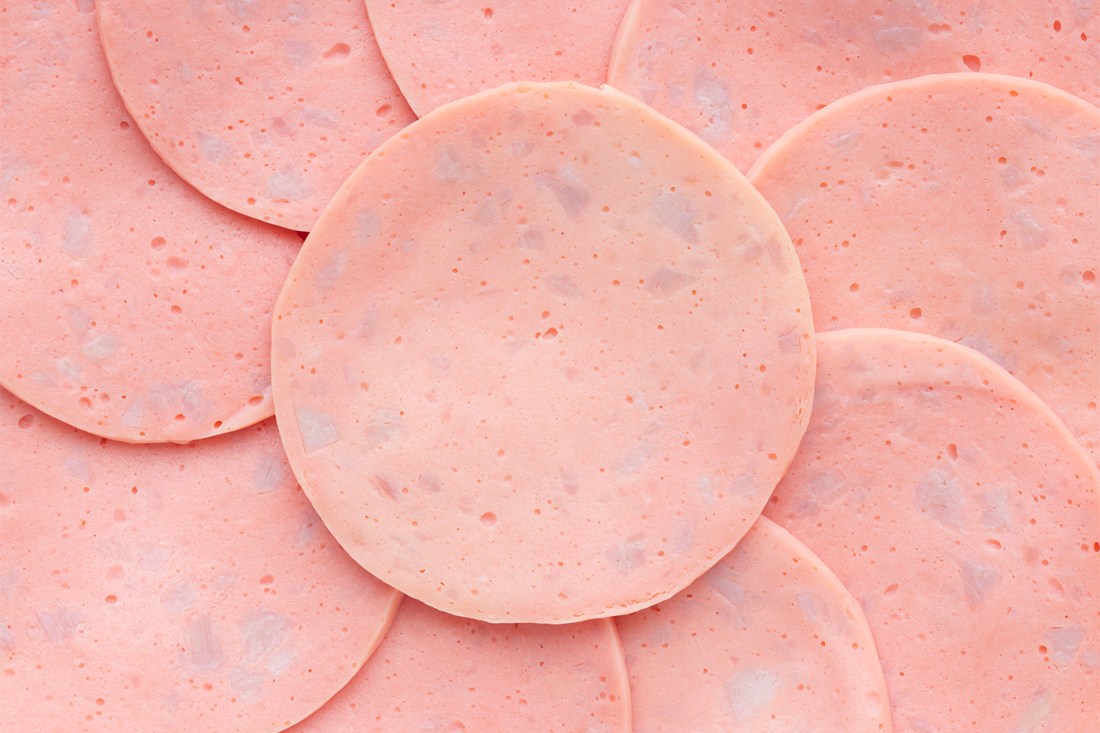 Close-up view of multiple slices of bologna arranged in overlapping layers.