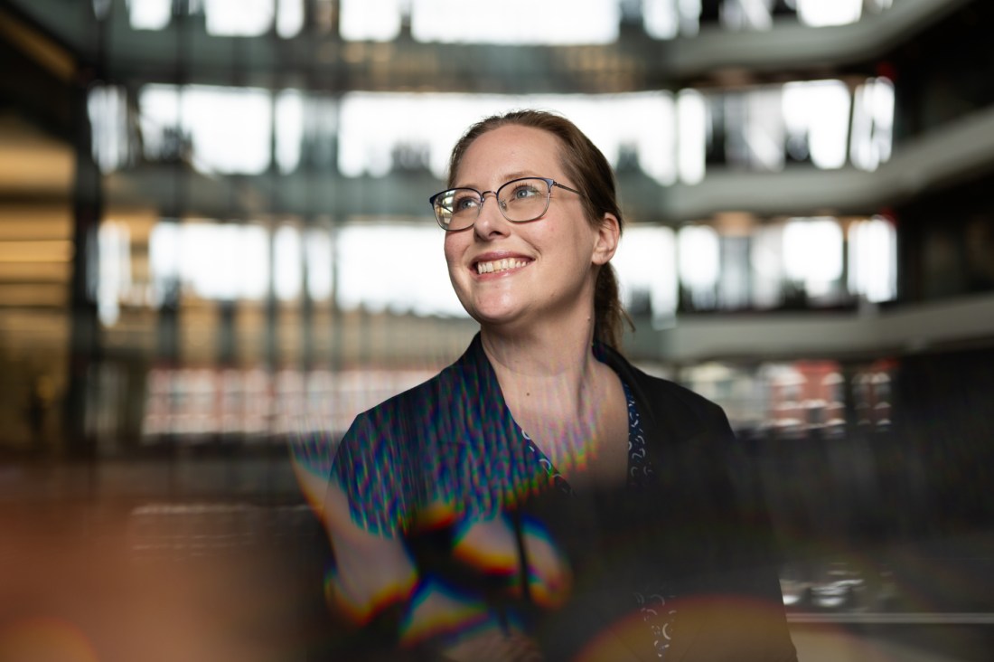 A smiling Jessica Oakes is depicted wearing a navy blue shirt.