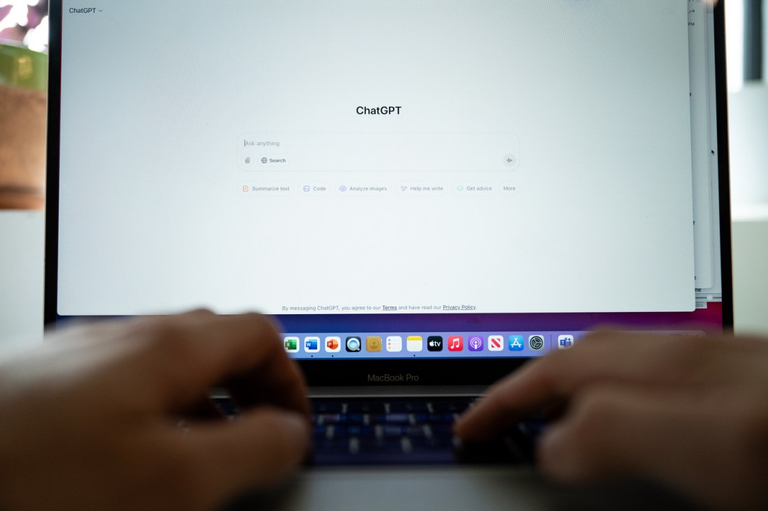 A person's hands typing on a laptop keyboard that is open to a ChatGPT screen.