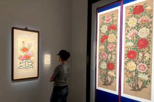 A person standing with their back to the camera facing a piece of art on the wall of a museum or other gallery space.