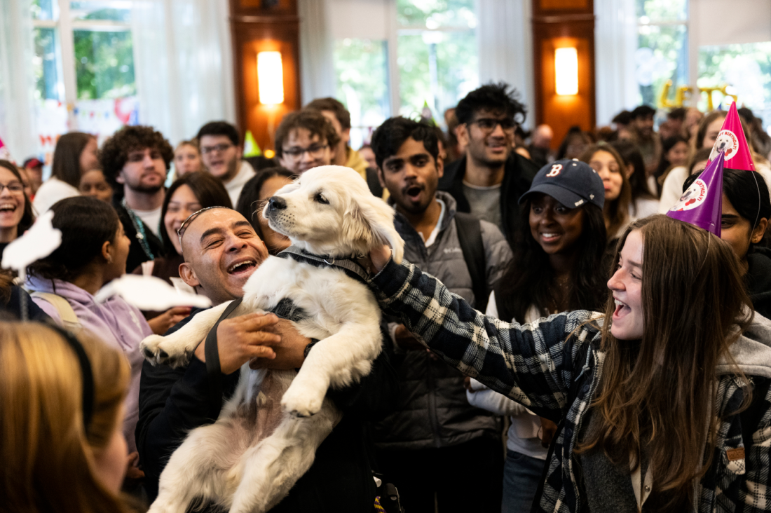 Ryder as a puppy being held up in front of a crowd