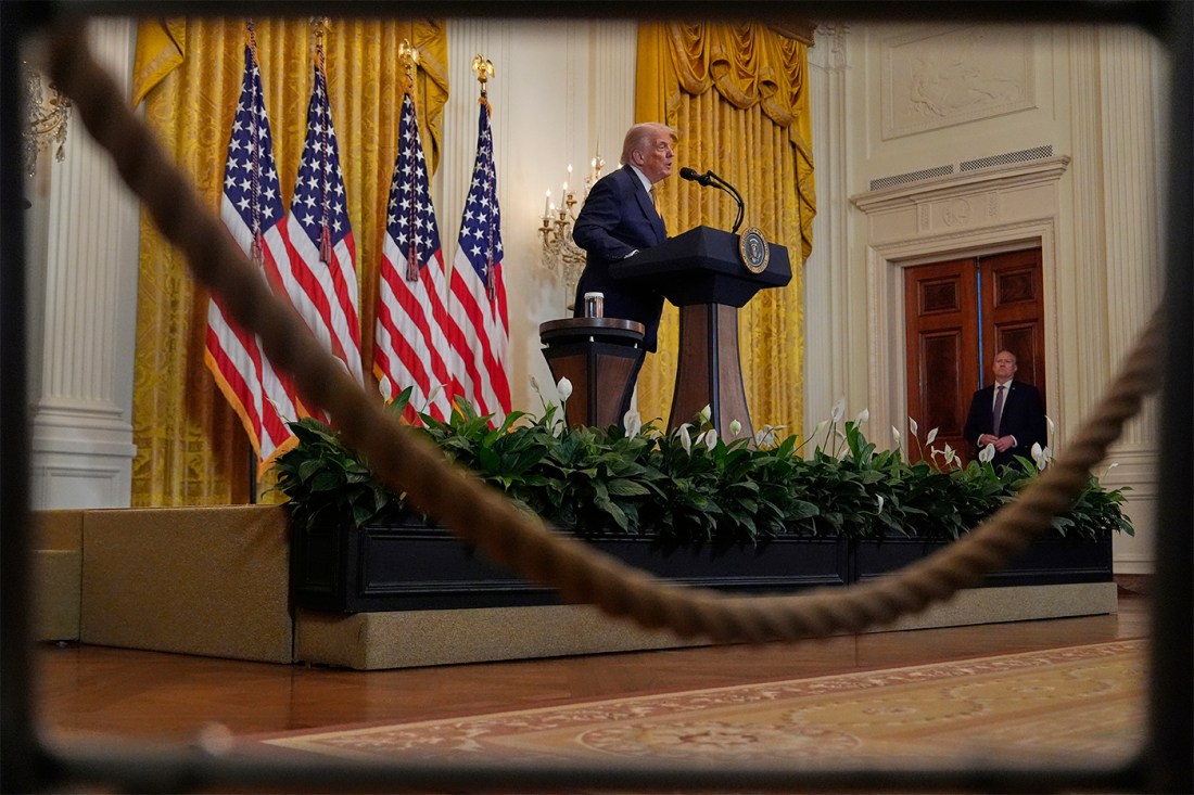 President Donald Trump appearing at a podium in front of several American flags.