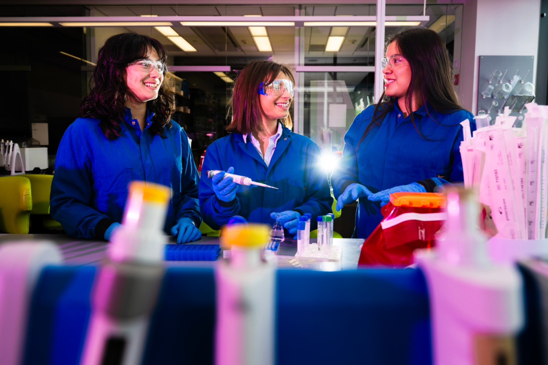 Three students in the lab working and laughing together