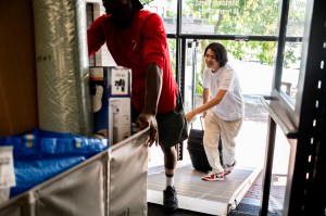 Students pushing a moving cart into a buildling