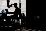 Silhouette of a person sitting at a table typing on a laptop.