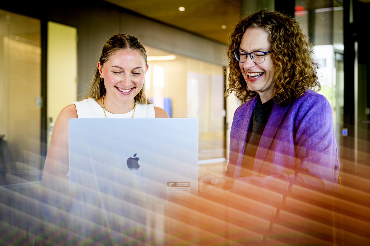 A young white woman smiles while being helped by Tiffany Kim, a middle-aged woman, who is an associate clinical professor, also smiling.