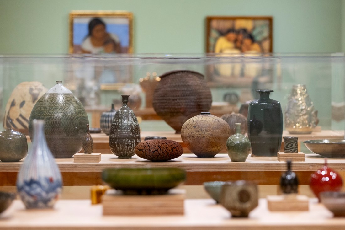A museum display case featuring a collection of historic ceramic pottery and vessels in various earth tones. 