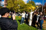 Students pose for a photo with a scarecrow on stilts for Friends and Family Weekend.