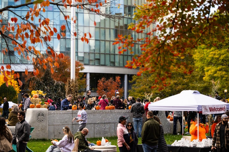 Crowds gather around hay bales, pumpkins, and tents on Centennial Common during Northeastern’s Friends and Family Weekend Fall Festival on a sunny autumn day.